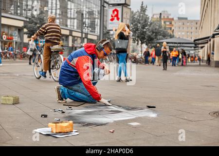 A street artist paints a realistic portrait on the floor of a city square. Street art. Berlin, Germany - 05.17.2019 Stock Photo