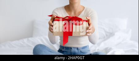 Lady Holding And Giving Wrapped Gift At Home Stock Photo