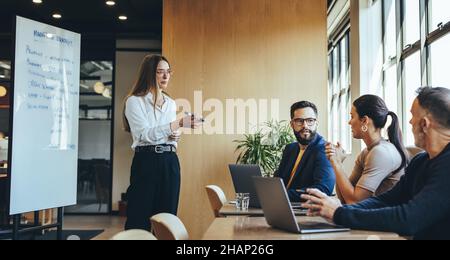Confident young businesswoman discussing her marketing strategy and ideas with her team. Female manager giving a presentation during a meeting with he Stock Photo