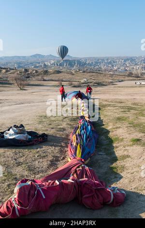 Ground crew members folding a hot air balloon after landing. Cappadocia,  Central Anatolia, Turkey Stock Photo