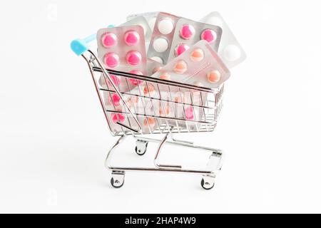 Many medicine pills, tablets and vitamins in a small supermarket shopping cart isolated on white background, pharmaceutical picture taken with soft fo Stock Photo