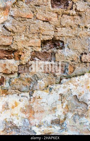 Old cracked weathered plastered brick wall background texture. Dirty peeled plaster wall with falling off flakes of paint Stock Photo