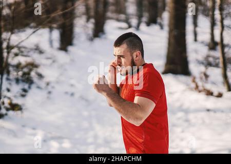 Muscular sportsman sparring in snowy forest at winter. Boxing in nature, winter sport, nature fitness Stock Photo