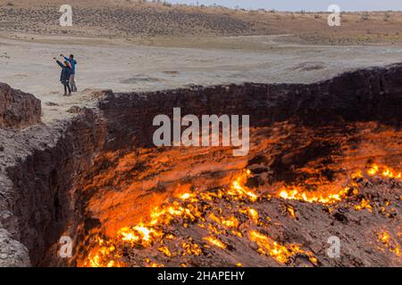 DARVAZA, TURKMENISTAN - APRIL 19, 2018: Tourists are taking selfie at Darvaza Derweze gas crater Door to Hell or Gates of Hell in Turkmenistan Stock Photo