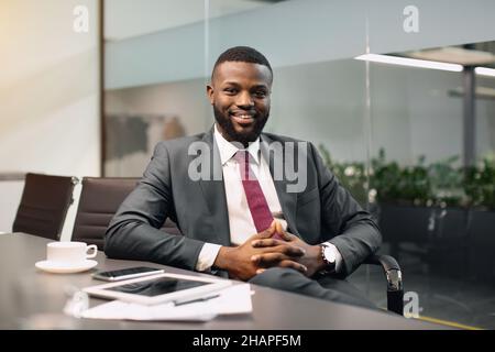 Cheerful black guy CEO sitting at conference hall Stock Photo