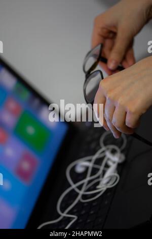 Closeup of woman's hands holding glasses over the laptop Stock Photo