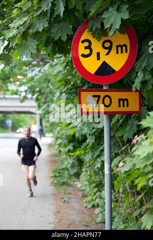 Stockholm, Sweden - June 7, 2010: A bridgde height sign in the foreground and a blurred runner running towards the camera. Indicates a 3,9 meter high Stock Photo