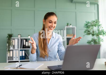 E-learning. Positive female teacher having video conference call using laptop, talking to webcam Stock Photo