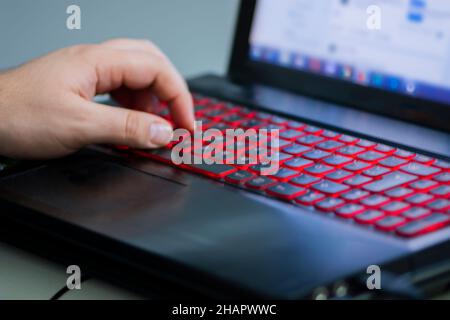 Man's left hand on the illuminated laptop keyboard Stock Photo