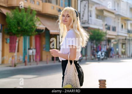 Young teenage blonde walking along street of summer tourist city Stock Photo