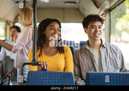 Cheerful asian guy and black lady taking bus together Stock Photo