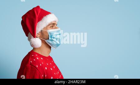 Profile Portrait Of Young Man In Santa Hat And Medical Face Mask Stock Photo