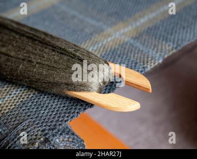 Shuttle with dark thread on the hand woven fabric, close up. Handloom weaving Stock Photo