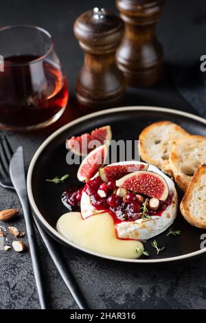 Baked camembert cheese with cranberry jam and nuts on a plate. Gourmet meal Stock Photo