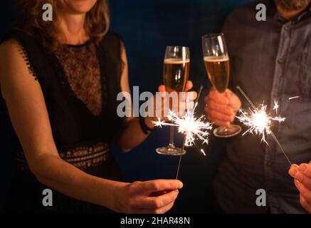 couple holding sparkles and champagne glasses Happy New Year Stock Photo