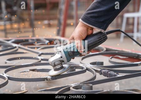Metal grinding with angle grinder. Male hand and instrument close-up, side view. Stock Photo
