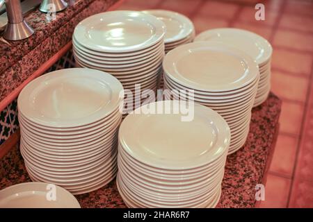 Clean white plates ready at table in buffet restaurant Stock Photo