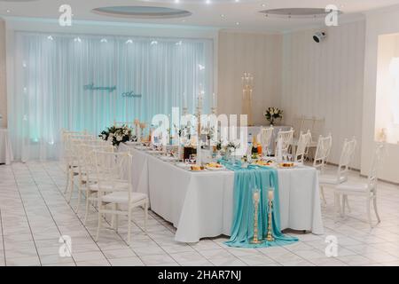 Wedding Banquet hall decorated with flowers. Table setting at a luxury wedding reception. Served for banquet tables in a luxurious interior. Stock Photo