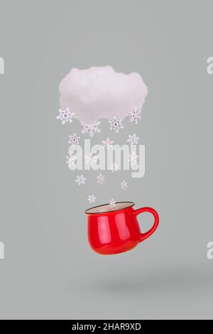 Creative concept with cloud, falling winter snowflake and mug on gray background. Minimal winter holidays concept. Stock Photo