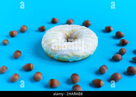 Donut with hazelnuts on a blue background, close up Stock Photo