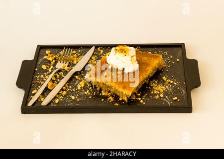 Traditional Turkish Kadayif Dessert With Walnuts and Clotted Cream sliced on tray Stock Photo