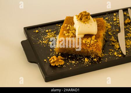 Traditional Turkish Kadayif Dessert With Walnuts and Clotted Cream sliced on tray Stock Photo