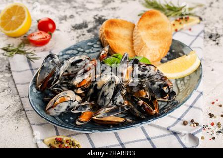 Mussels in a creamy sauce. Served on a plate with bread toast. Stock Photo