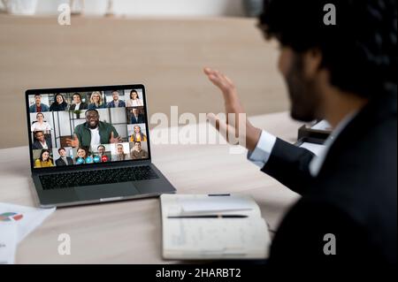 Indian successful businessman, ceo or manager communicates via an online conference with colleagues of different nationalities, discusses project, brainstorms employees, waves his hand Stock Photo