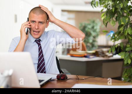 Irritated businessman having difficult phone talk Stock Photo