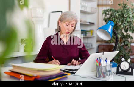 Stressed mature woman working in office Stock Photo