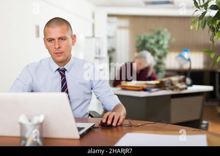 Focused businessman working with laptop at table in office Stock Photo