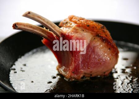 Rack of lamb searing in a black pan Stock Photo