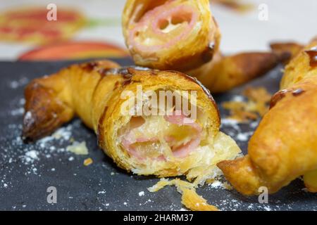 Freshly baked croissants stuffed with ham and melted cheese on a gray slate plate Stock Photo