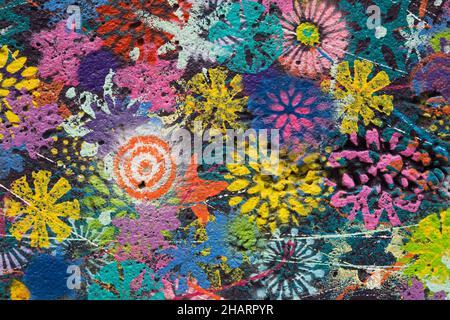 Colourful painted flower patterns on dark blue concrete wall. Stock Photo