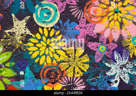 Colourful painted flower patterns on dark blue concrete wall. Stock Photo