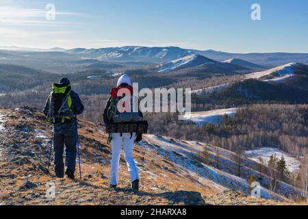A middle-aged couple go hiking in the alpine winter mountains at dawn. Stock Photo