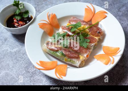 Summer Roll (Goi cuon) is a Vietnamese snack with ingredients including rice paper, cassava roots, shrimp, sausages, fried eggs and vegetables. dipped Stock Photo