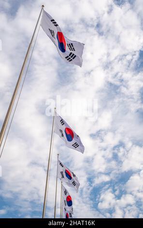 Flags of South Korea on a flagpoles against the cloudy sky Stock Photo