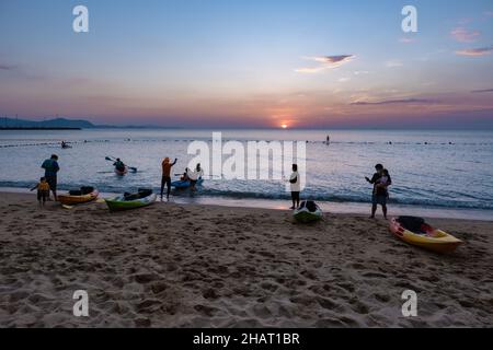 Najomtien beach Pattaya Thailand December 2021, sunset at a tropical beach with palm trees. Pattaya Thailand, people relaxing in front of a restaurant at the beach Stock Photo