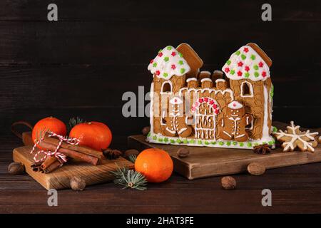 Beautiful gingerbread house and tangerines on black wooden background Stock Photo