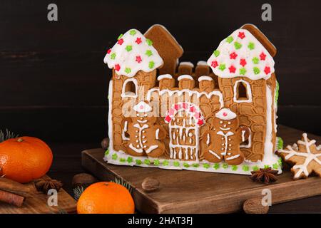 Beautiful gingerbread house and tangerines on black wooden background Stock Photo