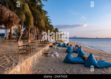 Najomtien beach Pattaya Thailand December 2021, sunset at a tropical beach with palm trees. Pattaya Thailand, people relaxing in front of a restaurant at the beach Stock Photo