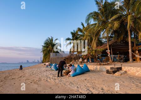 Najomtien beach Pattaya Thailand December 2021, sunset at a tropical beach with palm trees. Pattaya Thailand, people relaxing in front of a restaurant at the beach Stock Photo