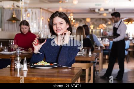 Portrait of young woman who is dining and drinking wine Stock Photo