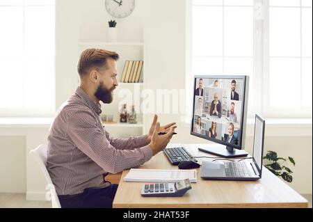 Man talking to a team of people during a remote business meeting on his computer Stock Photo