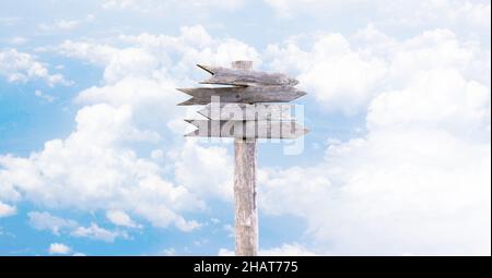 Four old wooden arrow pointers on a background of sky and clouds. Stock Photo