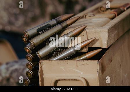 A metal ammunition tin with a belt of machine gun bullets coming from it. Showing a few bullets close up Stock Photo