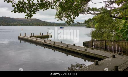 A jetty on Ullswater lake in the english lake district. There are a few small water craft moored in the distance Stock Photo