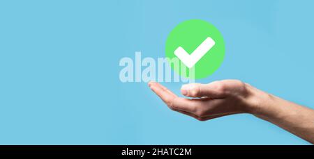 Hand holds green icon Check mark,Check Mark Sign, Tick Icon,right sign,circle green checkmark button,Done.On dark background.Banner.Copy space.Place f Stock Photo