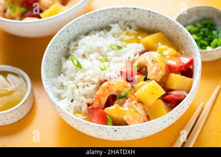 Rice with shrimp pineapple curry in a bowl, closeup view, yellow background Stock Photo